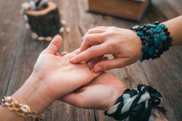 istockphoto-1199069814-612×612 Close up of fortune teller point her finger to woman's palm line and read her fortune. Palmistry cpncept