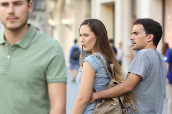 istockphoto-865675824-612×612 Disloyal woman looking another man and her angry boyfriend looking at her on the street